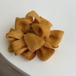 Vue détaillée du chouchou en tissu tressé jaune gingembre avec texture plissée florale