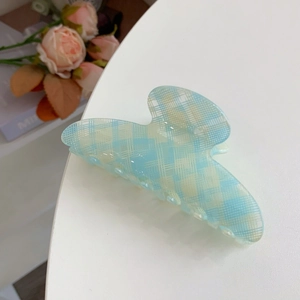 Eleganter hellblauer Haarklammer mit Karomuster auf weißem Tisch mit rosa Rose