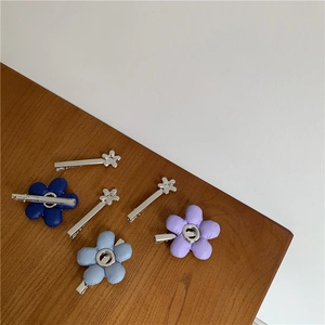 Detail van 3D stoffen bloem haarspelden in marineblauw, lichtblauw en paars