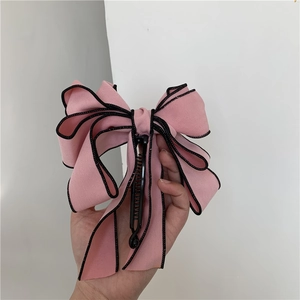 Detail view of multi-layer pink bow hair clip with black edges on a banana claw clip