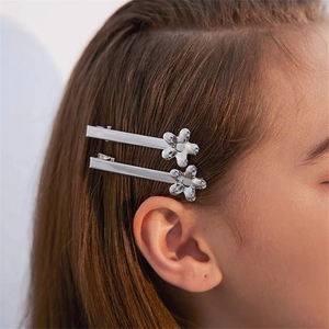 Detailopname van twee zilveren bloem haarspelden gedragen voor een schattige look