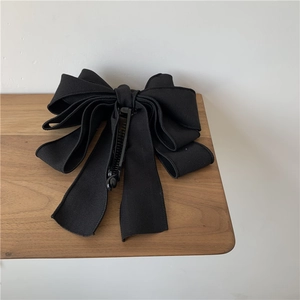 Macro detail of the layered black fabric ribbon structure and plastic banana hair clip