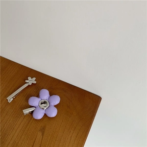 Detail van zilveren metalen haarspeld en paarse stoffen bloemclip op houten tafel