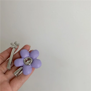 Detail van een paarse stoffen bloem haarclip en een zilveren metalen bloem haarspeldje