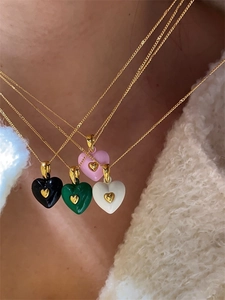 Détail de pendentifs coeurs émaillés en noir, vert, rose et blanc sur chaînes dorées