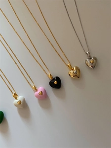 Vue détaillée de colliers double cœur en émail de diverses couleurs avec chaînes dorées