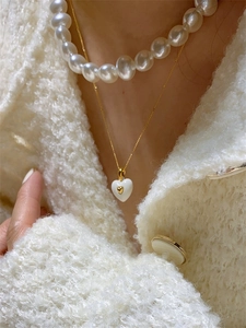 Gros plan d'un collier à double cœur émaillé avec une rangée de perles élégantes