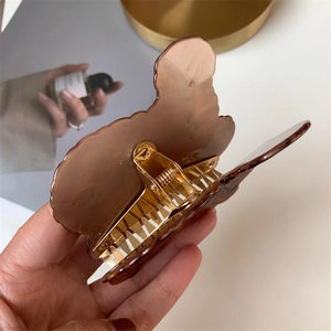 Detailed view of brown acetate poodle hair claw clip with golden metal spring mechanism