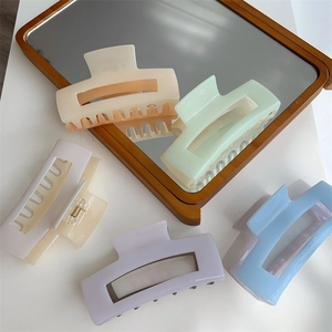 Detail of five pastel rectangular hair claws reflecting in a vintage wooden mirror