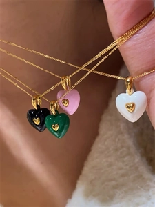 Détail de colliers avec cœurs en émail coloré noir rose vert et blanc sur chaîne dorée