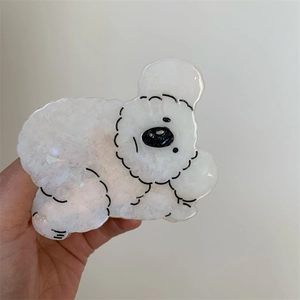 Close-up of cute white puppy hair claw clip with pearlescent acetate texture details