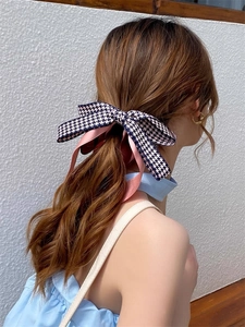 Détail montrant l'élégante barrette à motif pied-de-poule portée sur de longs cheveux