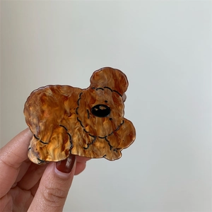 Macro detail of poodle-shaped acetate hair claw clip with brown tortoiseshell texture