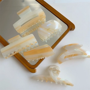 Détail de pinces à cheveux en acétate ambre et crème avec lettrage doré Barrette La France