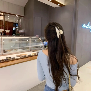 Pince à cheveux élégante blanc crème portée sur une coiffure demi-attachée au quotidien