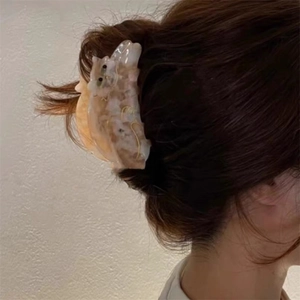 Detailed view of an acetate tortoiseshell cat hair claw clip on dark brown hair