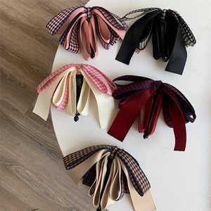 Vue détaillée de plusieurs pinces à cheveux banane avec nœuds et motifs pied-de-poule colorés