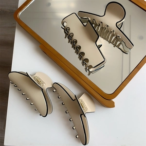 Vue détaillée de pinces à cheveux françaises crème avec bord noir et reflet miroir