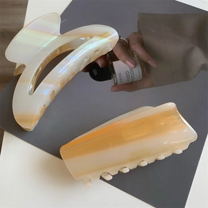 Détail de pinces à cheveux en acétate jaune crème avec finition nacrée irisée