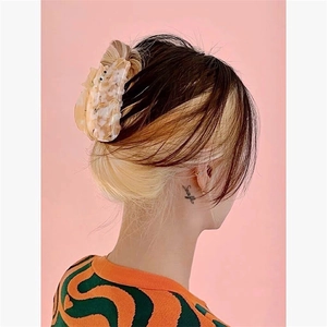 Detail view of large marble texture acetate hair claw clip worn on casual updo hair