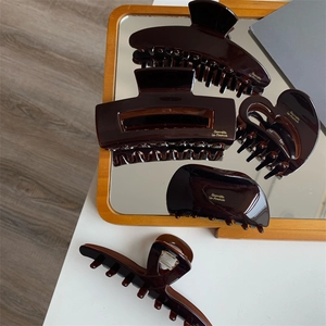 Chocolate tortoise shell hair claw set with gold logo on a wooden mirror background