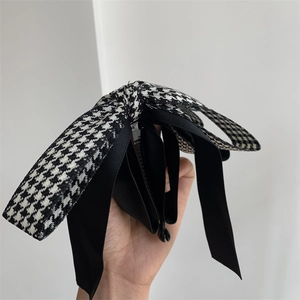 Détail de la pince à cheveux avec nœud en pied-de-poule et satin et pince banane noire