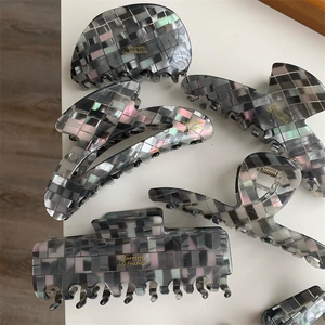 Détail de pinces à cheveux mosaïque grise avec fini perlé et ressort en métal doré