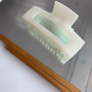 Macro detail of bicolored rectangular resin hair claw clip with cream and green finish