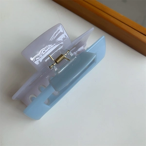 Detail shot of a two-tone lavender and light blue acrylic hair claw with a gold spring