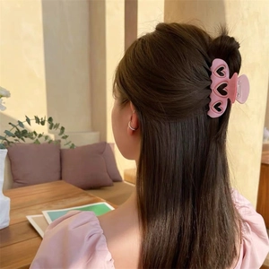 Gros plan d'une pince à cheveux rose avec cœurs stylisée sur des cheveux bruns