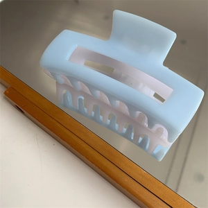 Detail view of light blue rectangular hair claw clip with smooth resin on a mirror surface