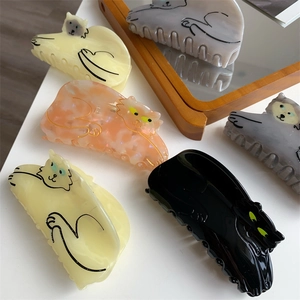 Close-up of cat-shaped hair claws in various acetate colors on a white surface