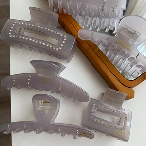 Détail de barrettes en acétate violet clair avec strass et lettrage doré élégant