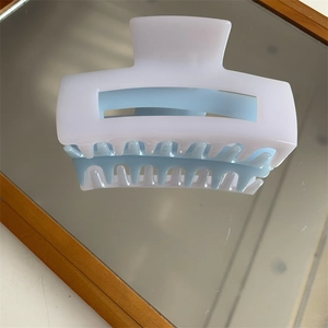 Detailed view of glossy square claw clip reflecting on a mirror surface