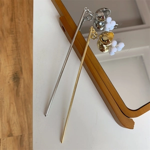 Détail d'épingles à cheveux dorées et argentées avec clochettes et perles sur un miroir