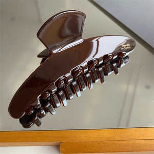 Close-up of deep brown acetate hair claw clip with elegant gold Barrette lettering