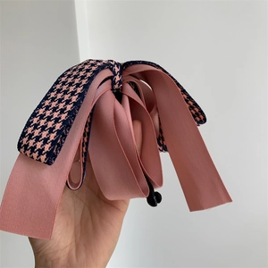 Détail de la pince à cheveux avec nœud en satin rose et motif pied-de-poule élégant