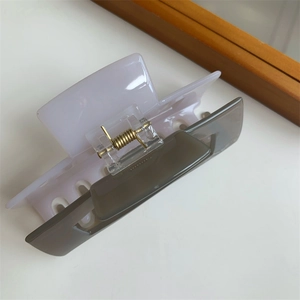 Detail view of rectangular hair claw clip with lilac and translucent grey color-block design