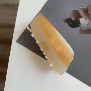 Détail macro de la pince à cheveux en acétate ambré avec lettrage doré Barrette La France