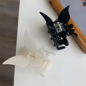 Détail des pinces à cheveux papillon évidées en noir et crème avec ressort doré