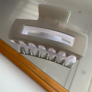 Detail shot showing large two-tone greige and white resin hair claw clip on mirror