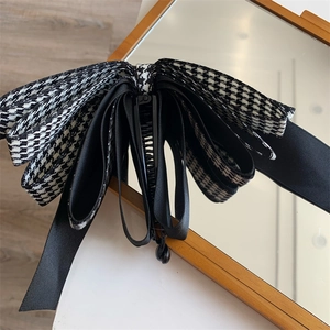 Détail d'une élégante pince à cheveux à motif pied-de-poule noir et blanc et ruban