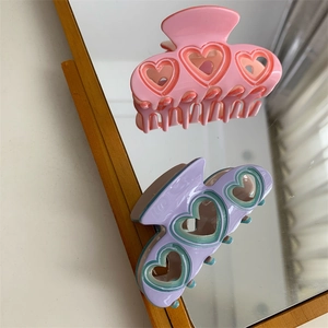 Vue détaillée de pinces à cheveux coeur évidé en rose et violet avec reflet de miroir créatif