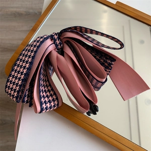 Détail d'un nœud papillon en satin rose et motif pied-de-poule sur un miroir