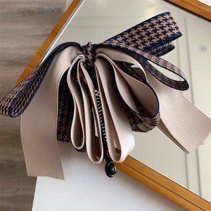 Détail d'un nœud papillon élégant en satin et pied-de-poule sur une barrette banane chic