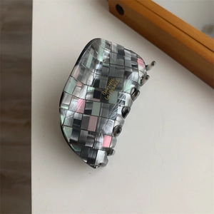 Détail d'une grande pince à cheveux à damier avec fini nacré et lettrage doré