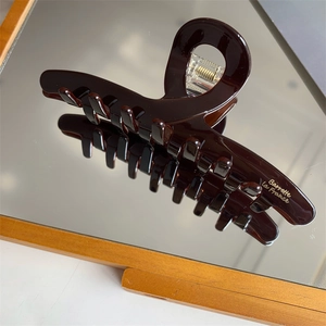 Close-up of brown acetate hair claw clip with golden Barrette La France logo detail