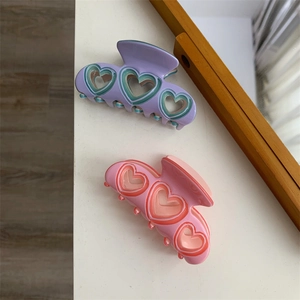 Gros plan des pinces à cheveux coeur violet et rose avec une finition gelée