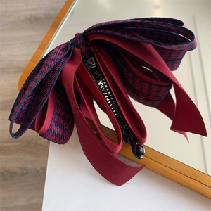 Détail de la pince banane élégante avec nœud en satin rouge et motif pied-de-poule