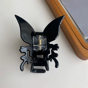 Vue détaillée d'une pince à cheveux papillon noir brillant au design ajouré élégant